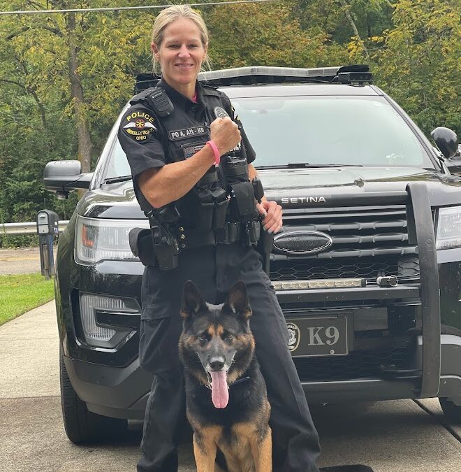 Officer and K-9 standing in front of cruiser