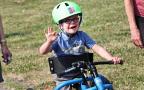 child on bike waving at camera
